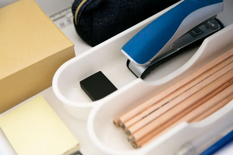 Close-up of an office drawer organized with pencils, stapler, sticky notes and more