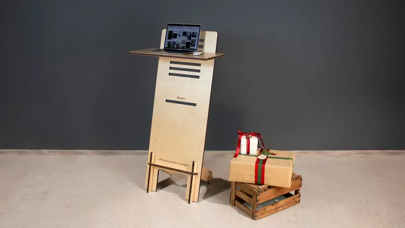 A modern wooden standing desk with a laptop and gift boxes on a crate, perfect for a minimalist office setup