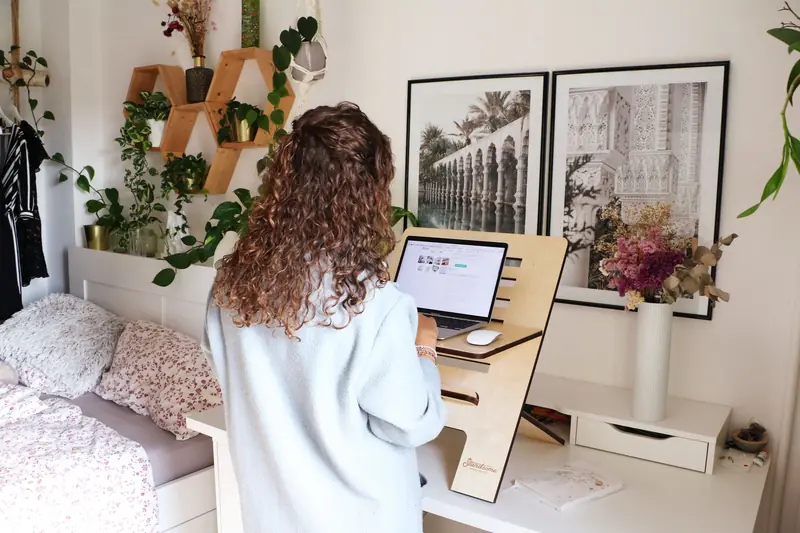 Woman using a laptop at home office standing desk with decor and laptop