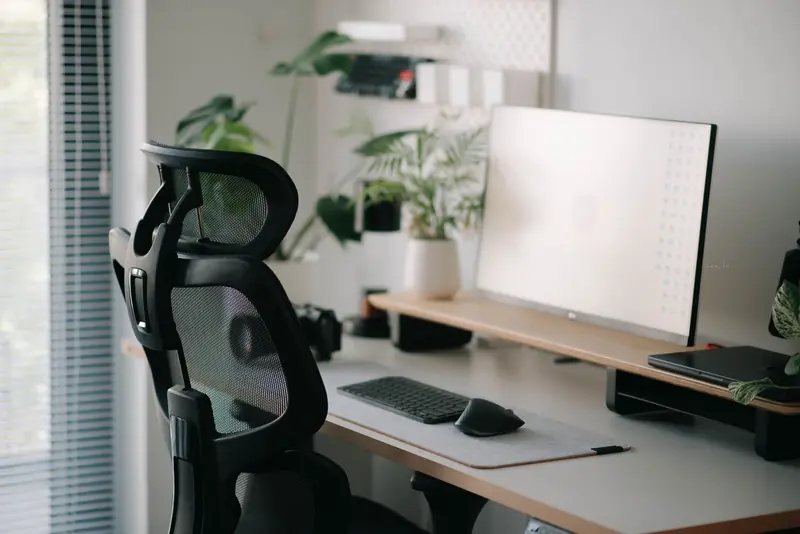 Stylish home office setup featuring an ergonomic chair, large monitor, and plants for a calming work environment