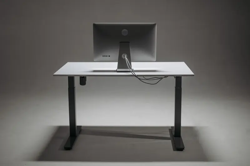 Rear view of a modern height adjustable standing desk with monitor and cable management